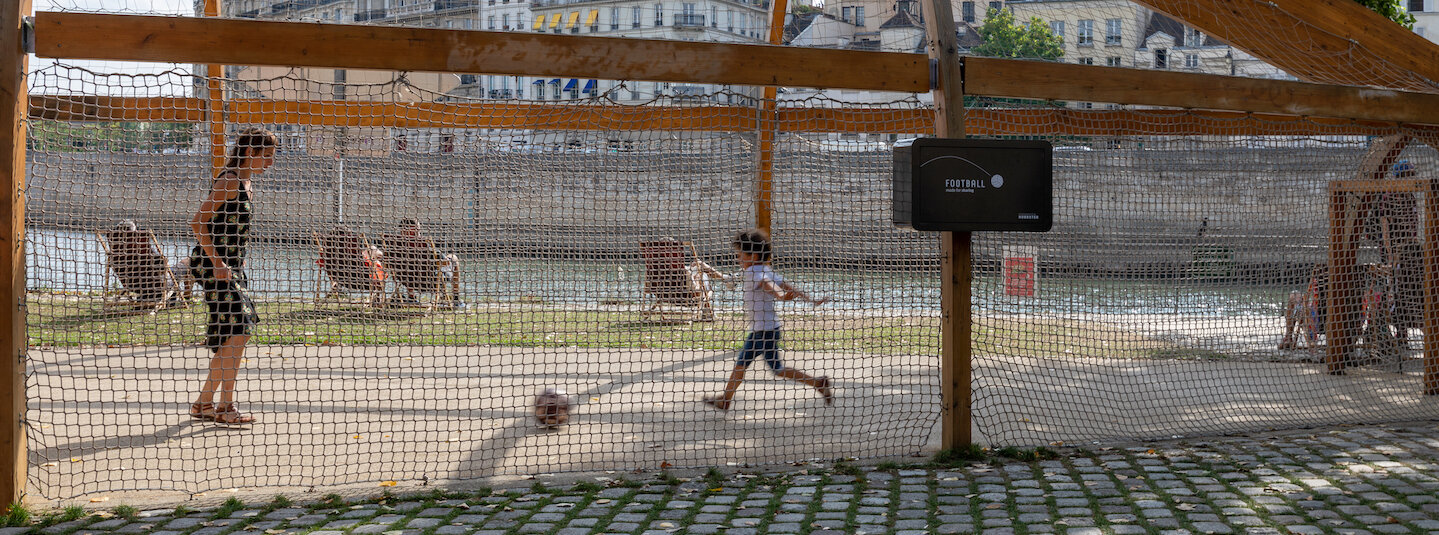 Hubbster opsat ved bane hvor dreng spiller fodbold med kvinde